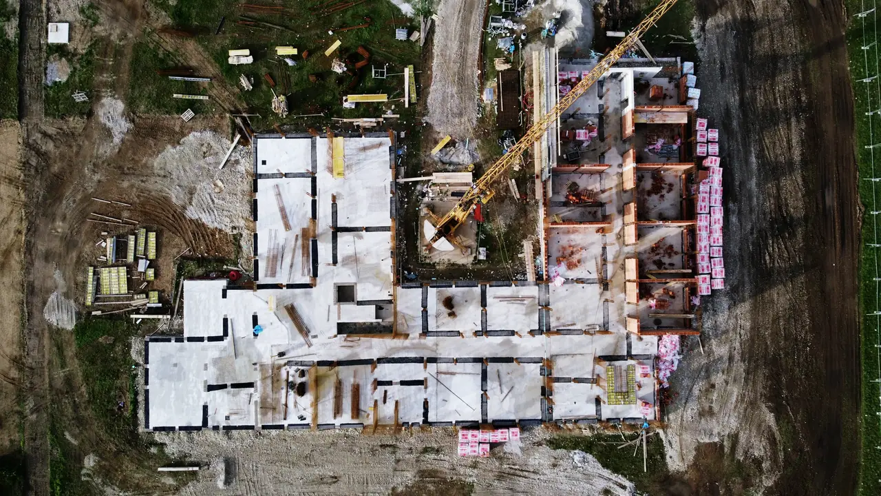 Pamje nga ajri e një kantieri: themelet, vinçi dhe depot e materialeve